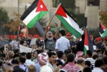 متظاهر يرفع علمي فلسطين والأردن