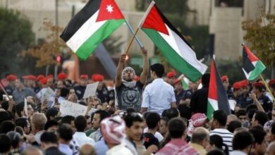 متظاهر يرفع علمي فلسطين والأردن