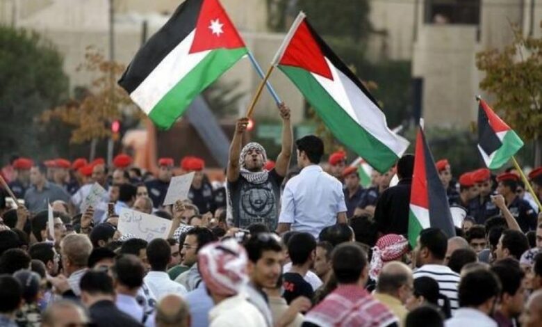 متظاهر يرفع علمي فلسطين والأردن